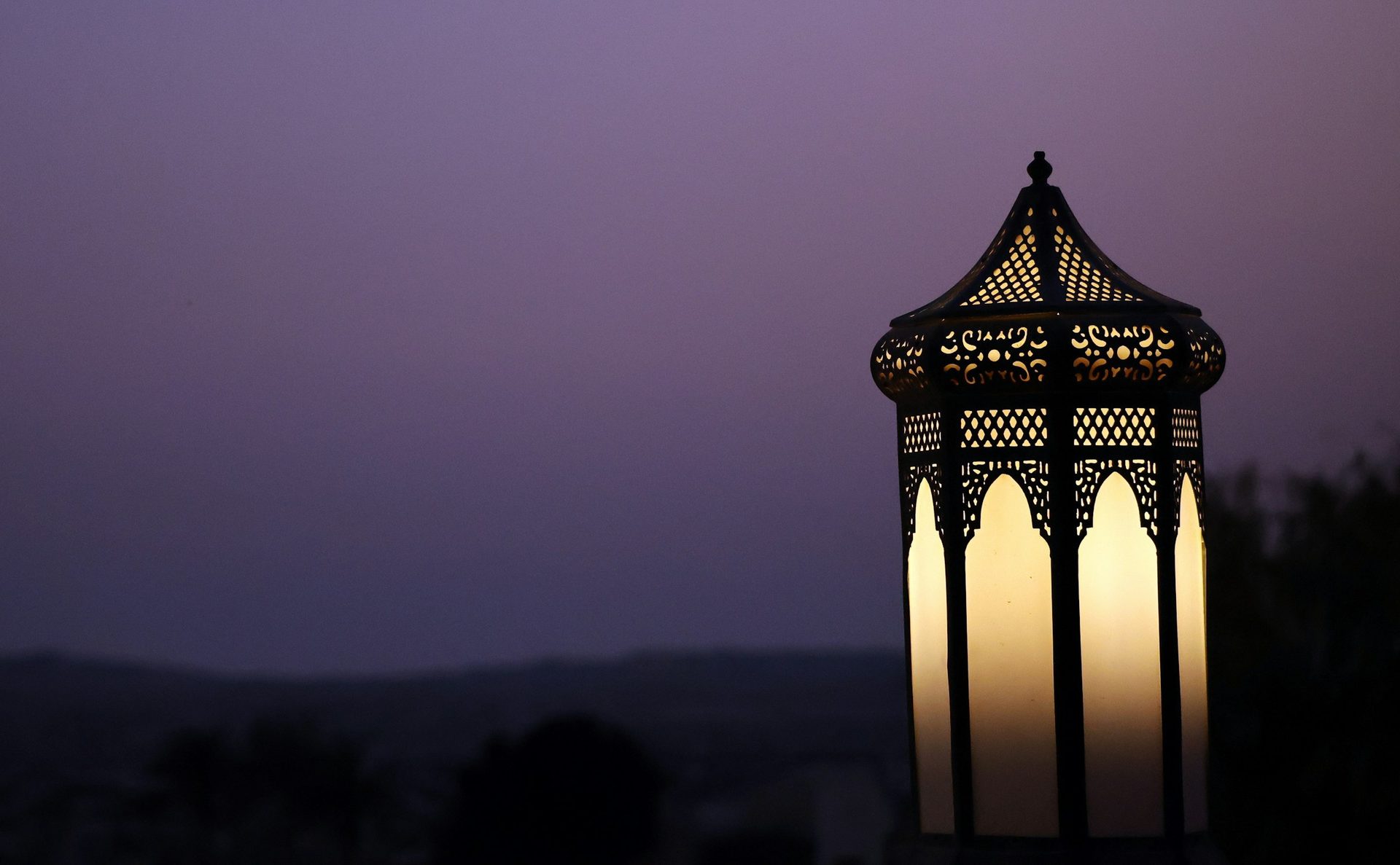 Világító, áttört mintás arab lámpás alkonyatkor Abu Dhabiban, lila égbolt előtt